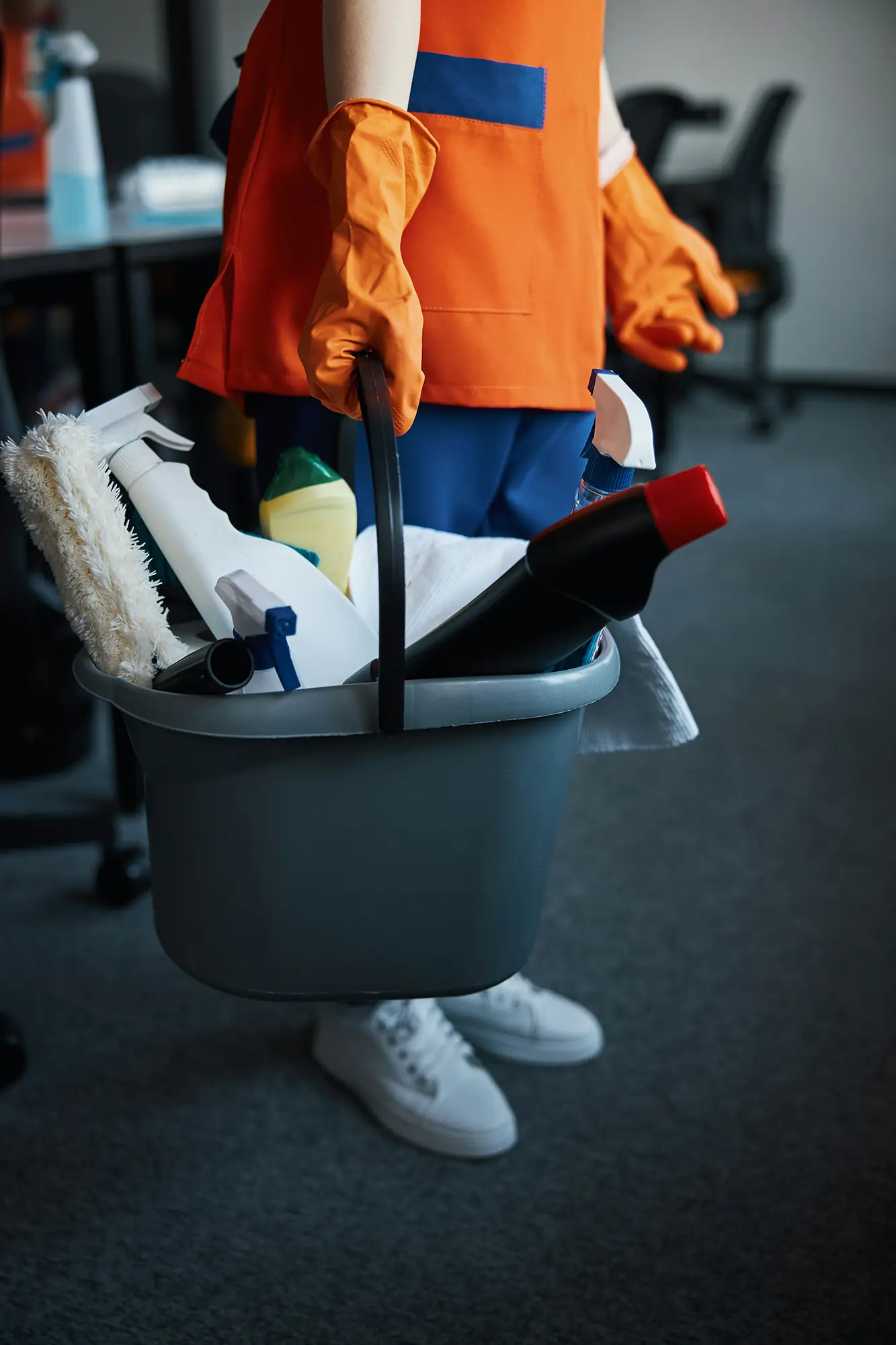 Person mit Handschuhe welche ein Eimer mit Putzmittel trägt